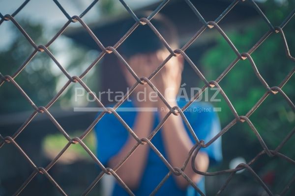 asian kid boy crying behind a metal chain wire mesh fence concept for child abuse human trafficking t20 grxe7g