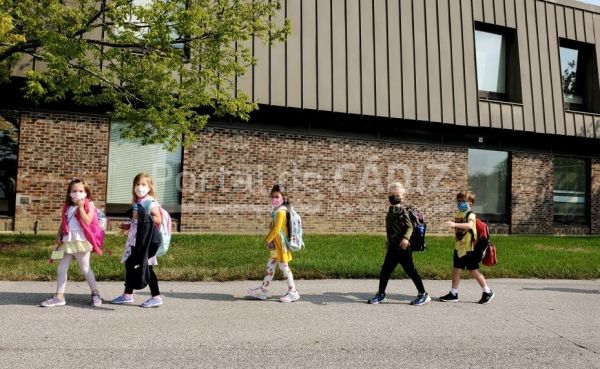 kindergarten girls and boys with backpacks and facemasks on head to school during the corona virus t20 vw4vm6