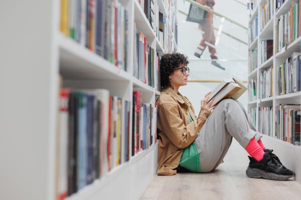 female student reads book sitting among the booksh 2023 02 21 19 44 19 utc