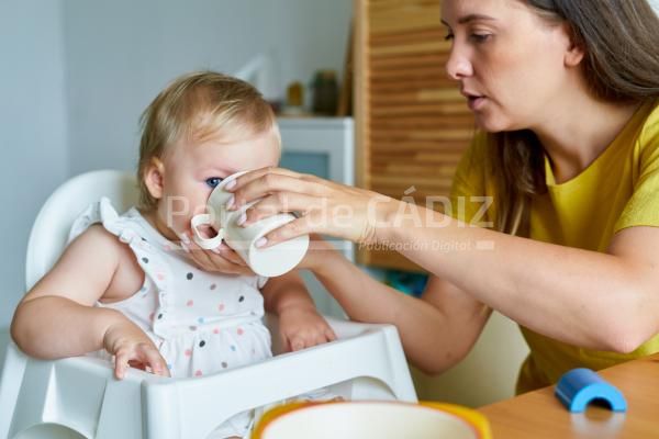 mother feeding daughter with baby formula in mug 2023 11 27 05 25 37 utc