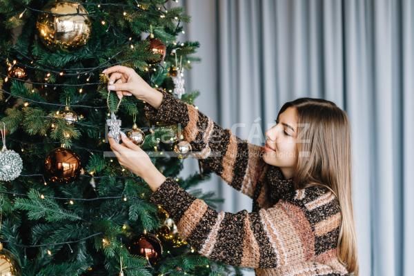 young woman decorates the christmas tree with toys 2023 11 27 04 57 52 utc